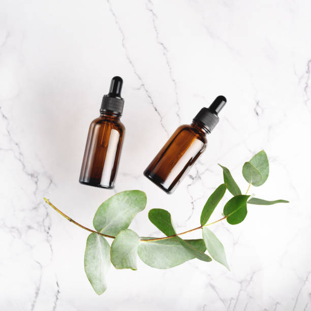 istock Glass dropper bottles on the white marble and eucalyptus background. 1284737422
