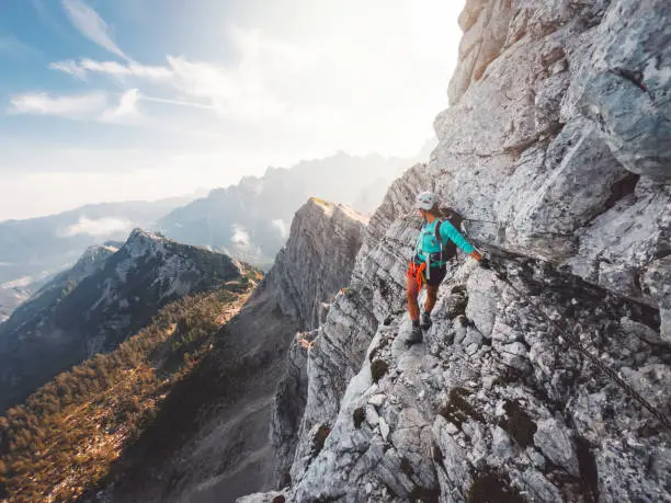 Photo of Climber on via ferrata trail, crossing a steep mountain edge