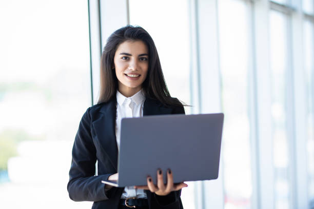 istock Modern business woman typing on laptop while standing in the office 1284737940