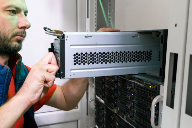 istock The technician installs a new battery pack into the uninterruptible power supply. Replacing the power module in the server room rack. Maintenance of data center equipment. 1284738084
