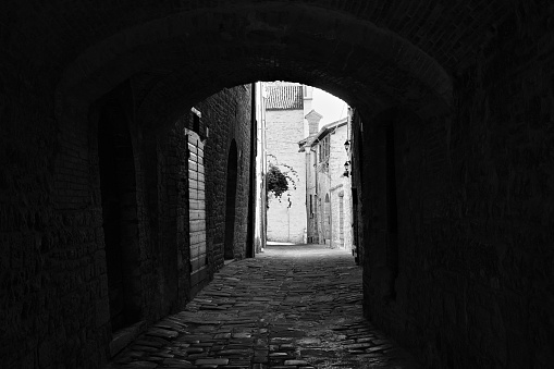 The view of an ancient alley under an architectural arch in a medieval Italian village (Gubbio, Umbria, Italy)
