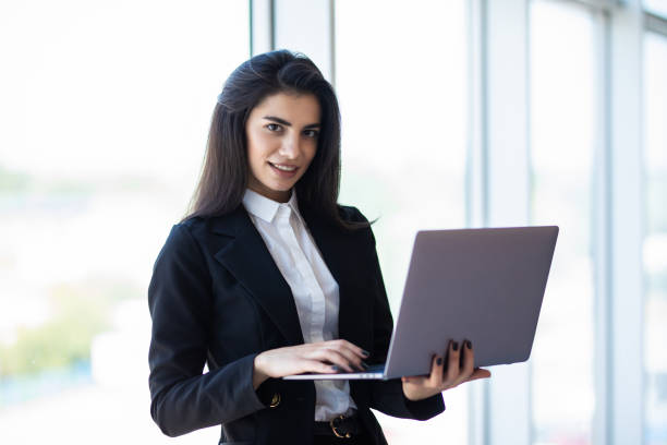 istock Modern business woman typing on laptop while standing in the office 1284739224