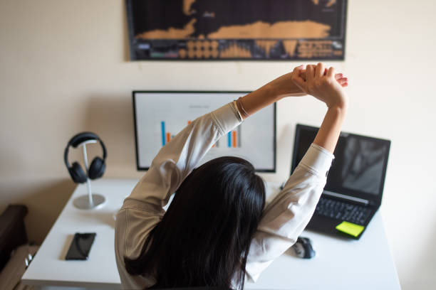 mulher se alongando enquanto trabalhava em um escritório doméstico - stretching - fotografias e filmes do acervo