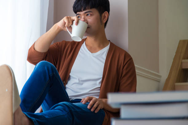istock A handsome man wearing knitted coat drinks coffee and looks out the window. Enjoy working day field recreation concept. 1284739893