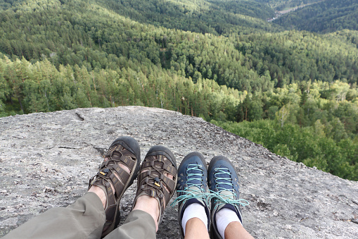 Male and female legs in trekking shoes on the top of the mountain , Altai Mountains, Belokurikha City, Russia