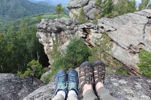 Male and female legs in trekking shoes on the top of the mountain ,rocks Ambarchiky, Altai Mountains, Belokurikha City, Russia