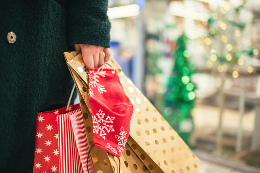 Woman's hand holding Christmas gifts in a shopping mall