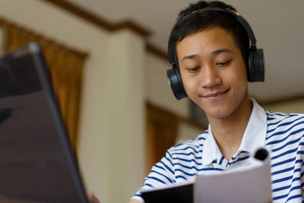 istock Happy young asian man with headphone learning by online class with teacher from video call 1284746074
