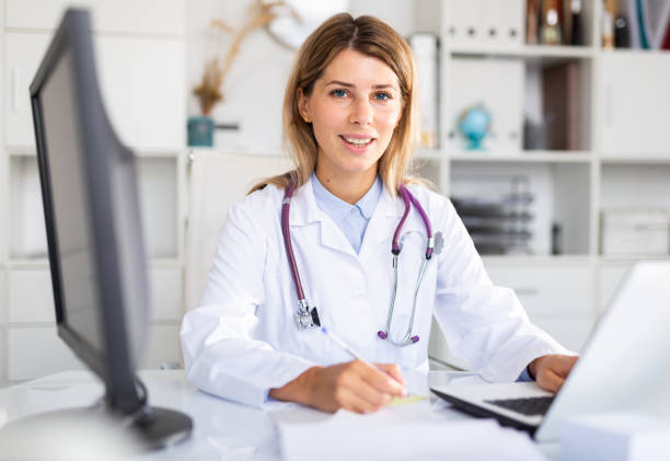 istock Woman doctor sitting at workplace with computer in office 1284751220