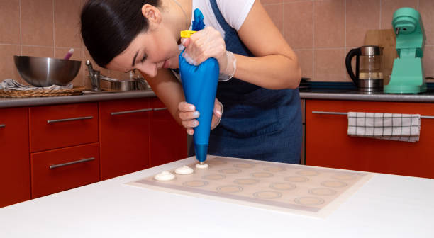 the girl puts the future macaroons on parchment. - fragility organization chef cake imagens e fotografias de stock