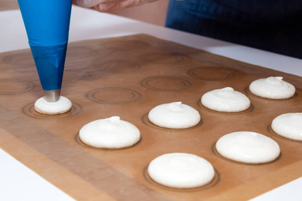 the batter for the macaron on the parchment. the process of cooking by a pastry chef. - fragility organization chef cake imagens e fotografias de stock