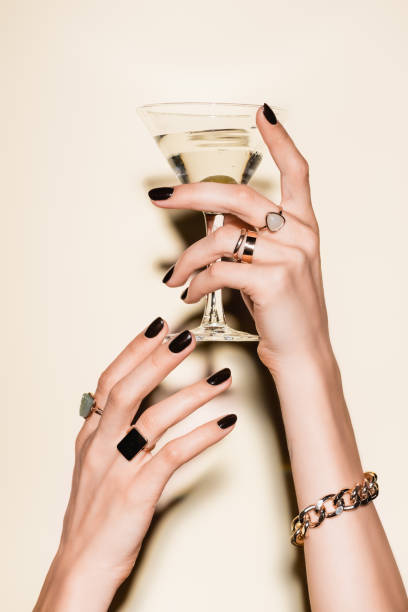 vista ritagliata di donna con anelli sulle dita tenendo bicchiere di martini con oliva su bianco - martini glass foto e immagini stock