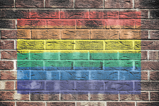 A Gay pride rainbow flag on brick wall background