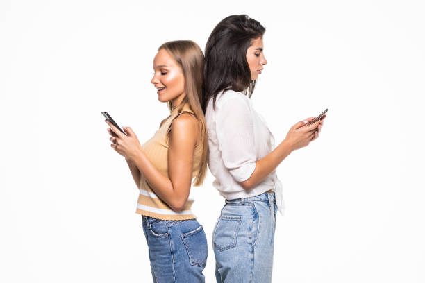 istock Young two women with phones turned each other's backs isolated on white background 1284757847