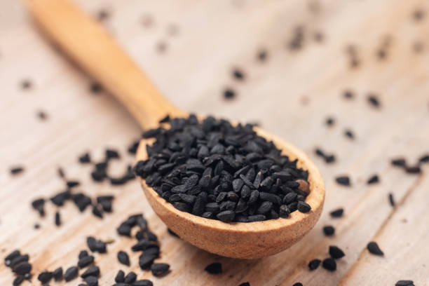 istock Black cumin seeds on wooden spoon on wooden background 1284758041