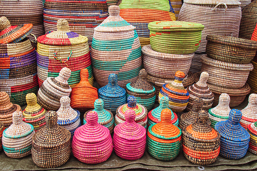 many african straw baskets on a market stand, with many colors and decorations