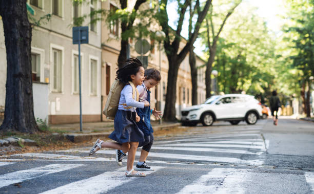 chicas pequeñas cruzando la calle al aire libre en la ciudad, concepto de coronavirus. - familia de cruzar la calle fotografías e imágenes de stock