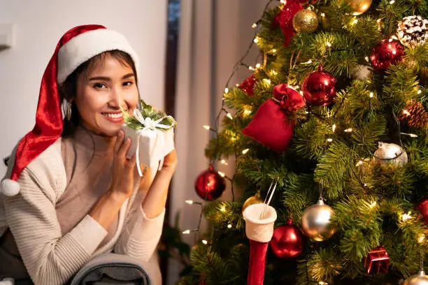 Beautiful asian woman holding Christmas ornament for decorate on christmas tree preparing for season greeting of merry christmas and happy holiday.