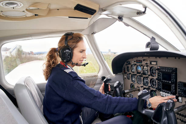 Woman Pilot Side view of a female pilot in the cockpit of an airplane touching some buttons. ultralight photos stock pictures, royalty-free photos & images