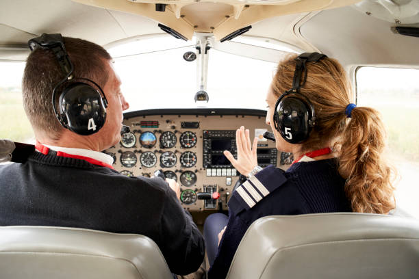 istock Back view of pilot trainee and female flight instructor in cockpit. 1284761252