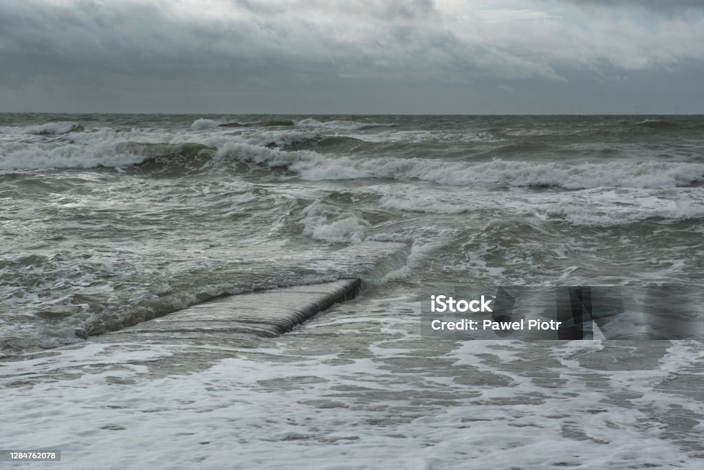 A sea waves covers a concrete groyne. Stromy weather in Brighton Grey winter by the English Channel Backgrounds Stock Photo