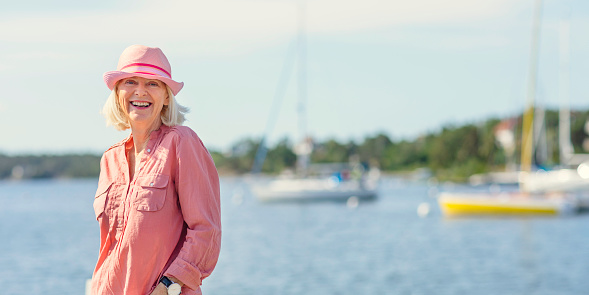 A woman in her sixties out by the sea on the coast of Stockholm, Sweden.