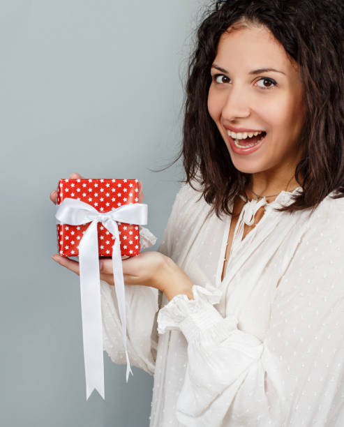 istock Young woman holding Gift package in hands close up 1284764357