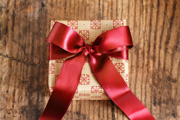 istock Gift box with bow made with red satin ribbon on wooden table 1284765430