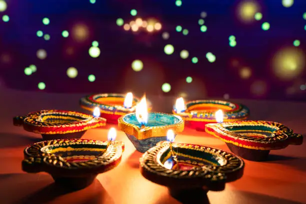 Photo of Indian festival Diwali, Diya oil lamps lit on colorful rangoli. Hindu traditional. Happy Deepavali. Copy space for text.