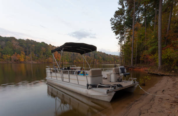 Pontoon boat at Falls Lake NC in autumn Pontoon boat beached at Falls Lake in North Carolina during the early fall pontoon boat stock pictures, royalty-free photos & images