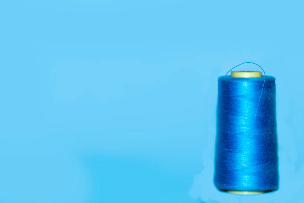 istock Background with a large and small blue spool of thread. They lie next to each other on a blue background 1284768512