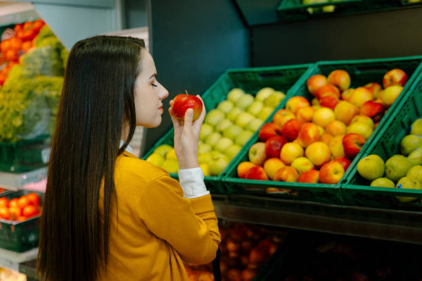 istock Woman sniffing apple in store 1284768696