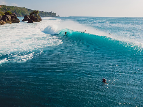 Aerial view with surfing at barrel wave. Blue perfect waves and surfers in ocean