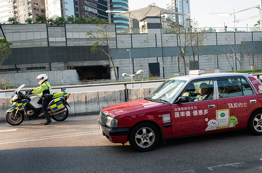 HONG KONG, CHINA; SEPTEMBER 30, 2018: Taxi driver and motorized police wait through heavy traffic