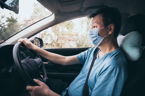istock Mid adult man driving on road with protective face mask to avoid infectious disease during global pandemic crisis 1284770209