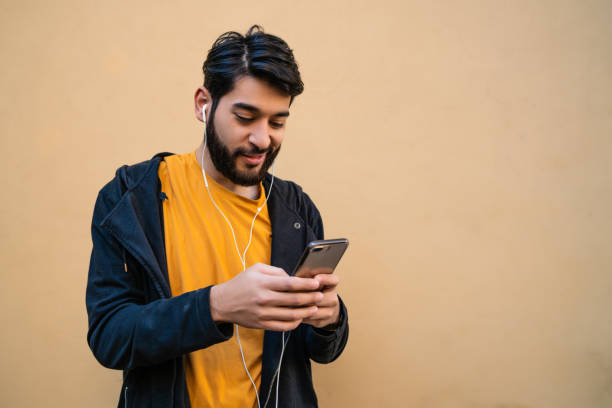 istock Latin man using his mobile phone with earphones. 1284770450