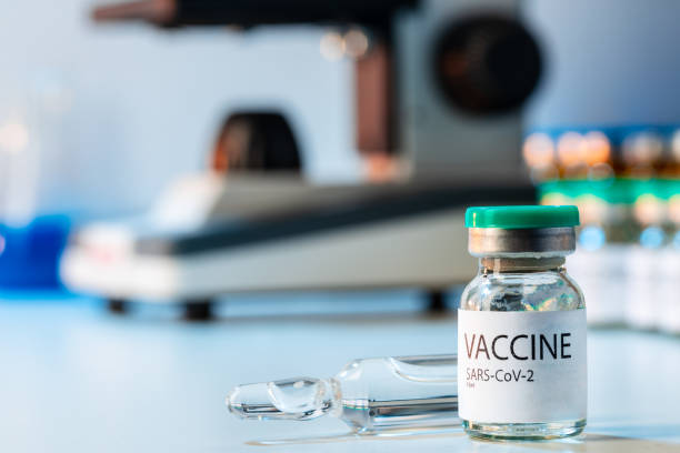 istock Vial of Covid-19 vaccine next to a microscope 1284773434