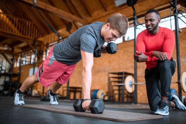istock Young man exercising with a personal instructor at the gym 1284774606