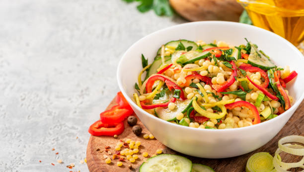 istock Vegetable salad with ptitim in a white bowl on a gray background. 1284777299