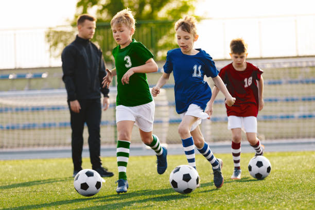 Young Boys Running On Football Training. Happy Kids on Soccer Sports Practice.  Children in Colorful Jersey Shirts Young Boys Running on Football Training. Happy Kids on Soccer Sports Practice.  Children in Colorful Jersey Shirts club soccer photos stock pictures, royalty-free photos & images