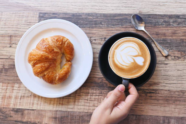 istock Coffee and croissant on wooden table, top view . 1284778208