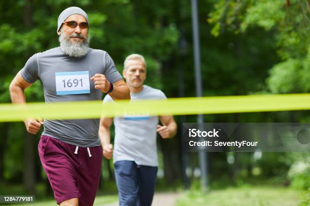 Two Men Finishing Marathon Stock Photo - Download Image Now - Running, Senior Adult, Sports Race