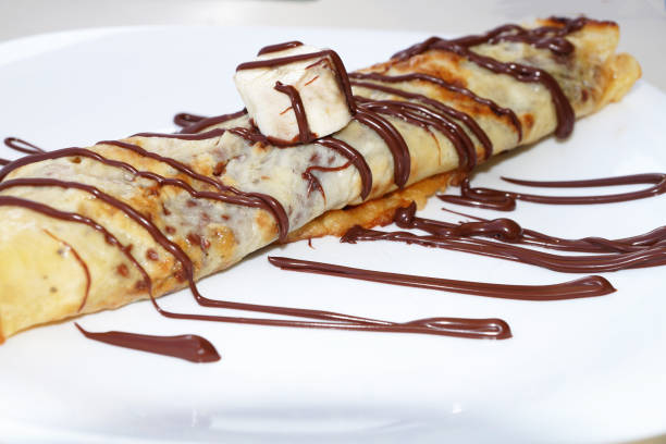 istock pancake with banana, doused with chocolate on a plate close-up 1284779893