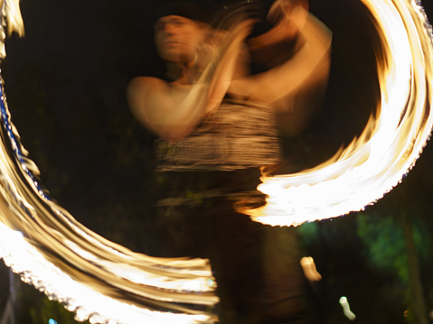 Moscow, Russia - October 28, 2020: Blurred motion of performer of the fire show  with burning torches. Street free money show. Autumn night. Bright golden rounds. Light vortex. Concepts of the beauty in the abstraction and creativity.