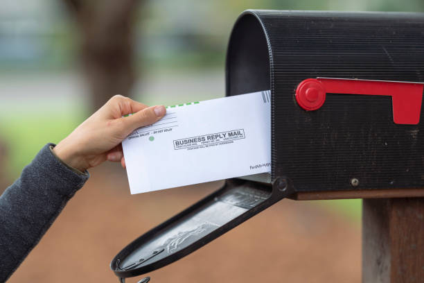 istock Female Hand Placing Ballot In Mailbox 1284781189