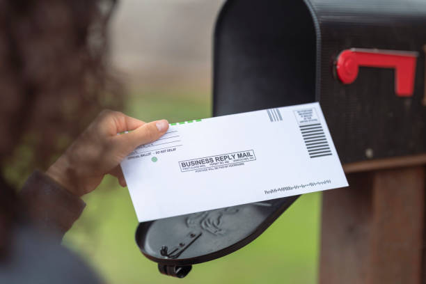 istock Female Hand Placing Ballot In Mailbox 1284781191