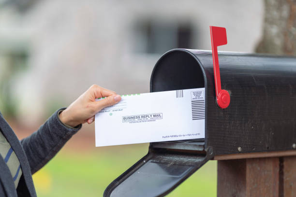 istock Female Hand Placing Ballot In Mailbox 1284781198