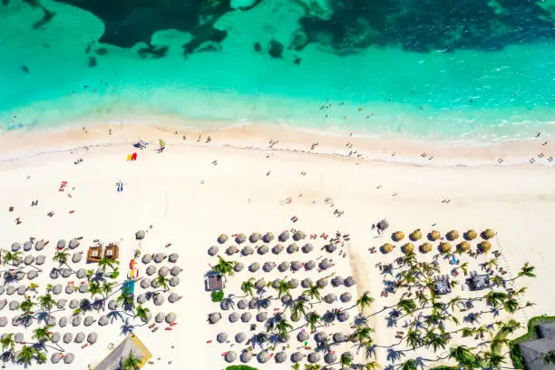 Beach vacation and travel background. Aerial drone view of beautiful atlantic tropical beach with straw umbrellas, palms and boats. Bavaro beach, Punta Cana, Dominican Republic