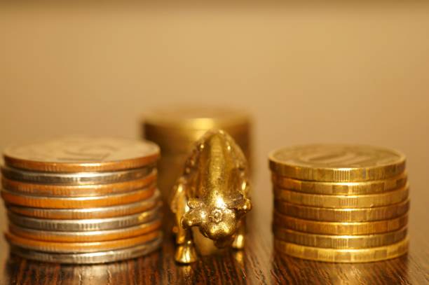 istock Metal bull with coins on a gold background. 1284781803