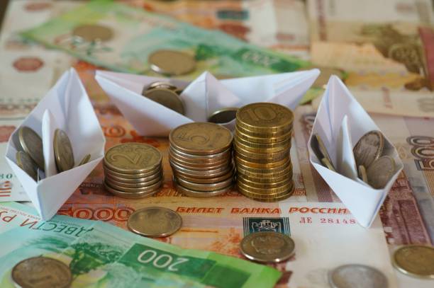 Several paper boats loaded with coins.